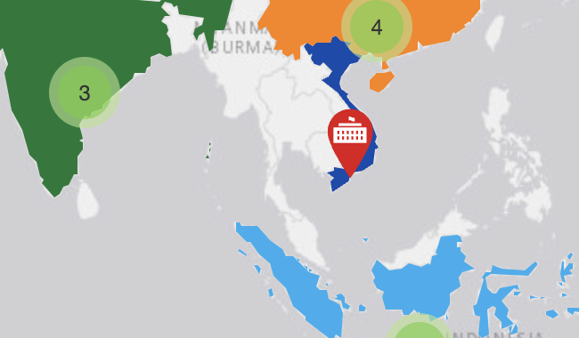 Background is a map of the world with countries in white and oceans in grey. The map is centered on South-East Asia. The bottom part of India is visible and coloured dark green. The bottom half of China is visible an coloured orange. The whole of Vietnam is visible and coloured dark blue, and the majority of Indonesia is visible and coloured light blue. Green circles with numbers in them in India and China represent diplomatic missions in the country. A red pin icon with a government building in Vietnam represents the consulate there.